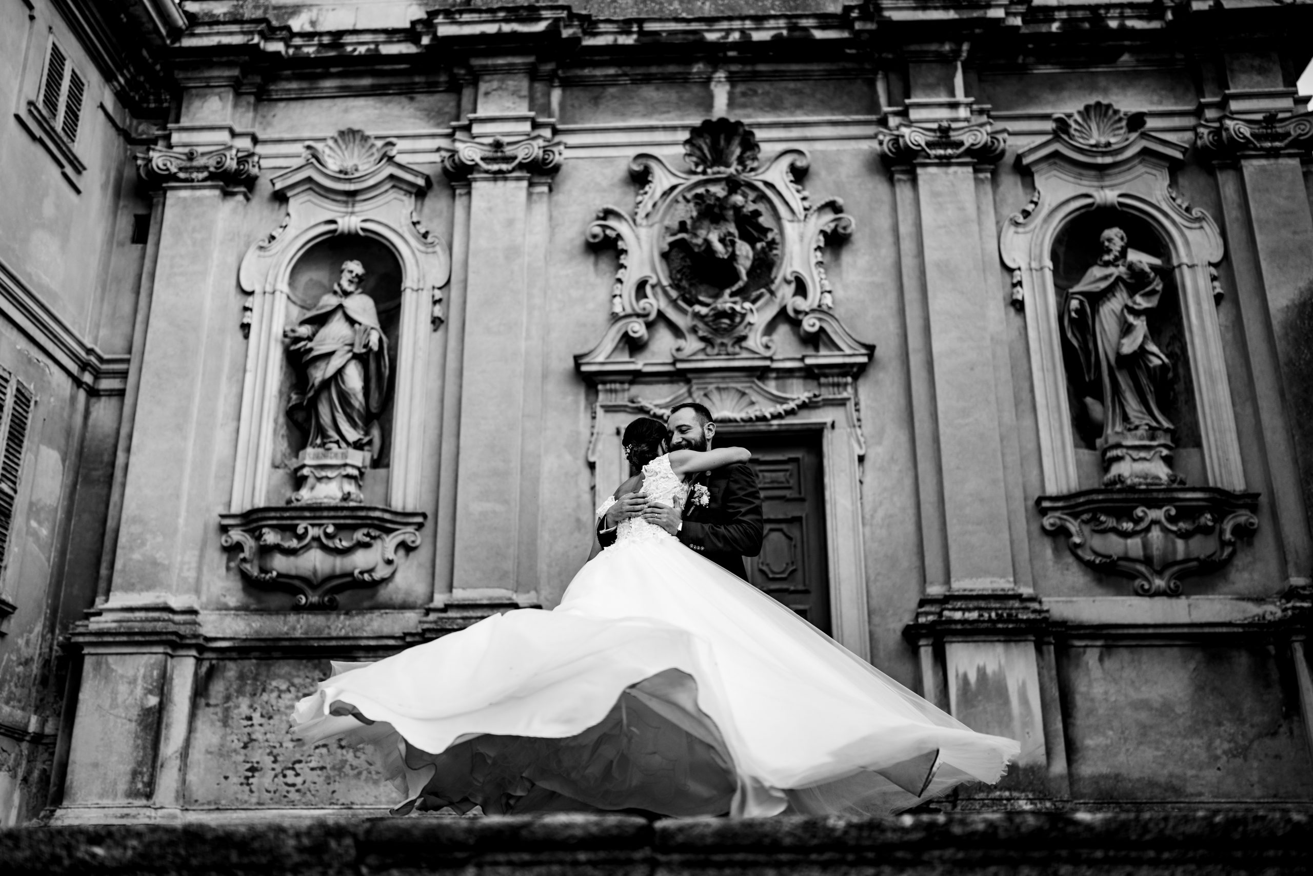 Lo sposo abbraccia la sposa e la fa girare, catturato in bianco e nero a Villa Antona Traversi.