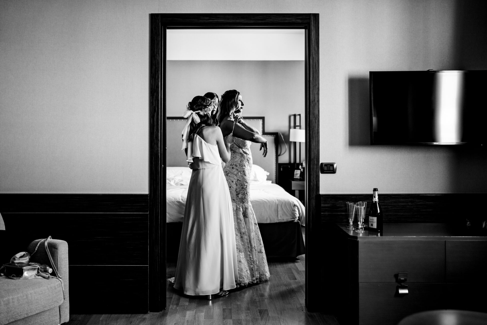 La sposa indossa il suo abito da sposa con l'aiuto delle damigelle a La Madonnina di Barni.