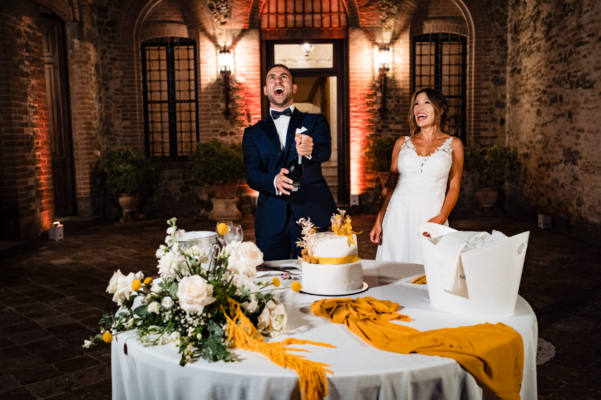 Lo sposo apre con energia una bottiglia di champagne, pronto per il brindisi. Fotografia scattata da Paolo Lamperti Fotografo Matrimonio Varese al Castello di Tabiano.