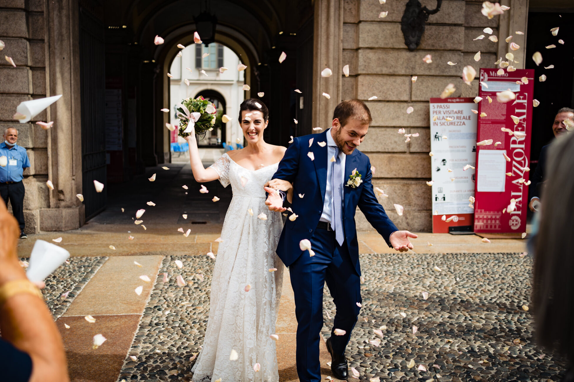 Gli invitati lanciano i petali di rosa sugli sposi all’uscita da Palazzo Reale Milano durante il Matrimonio Chiostri San Barnaba.